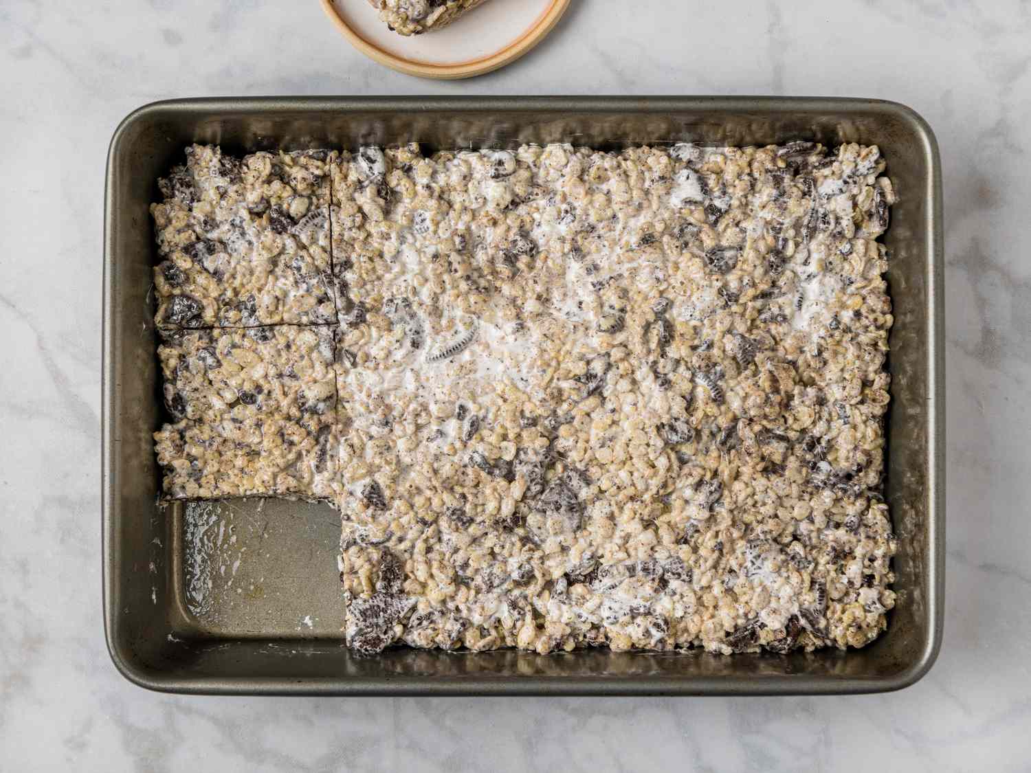 A 9x13-inch baking pan filled with thick, gooey Rice Krispie treats, lightly golden on top, sitting on a kitchen counter