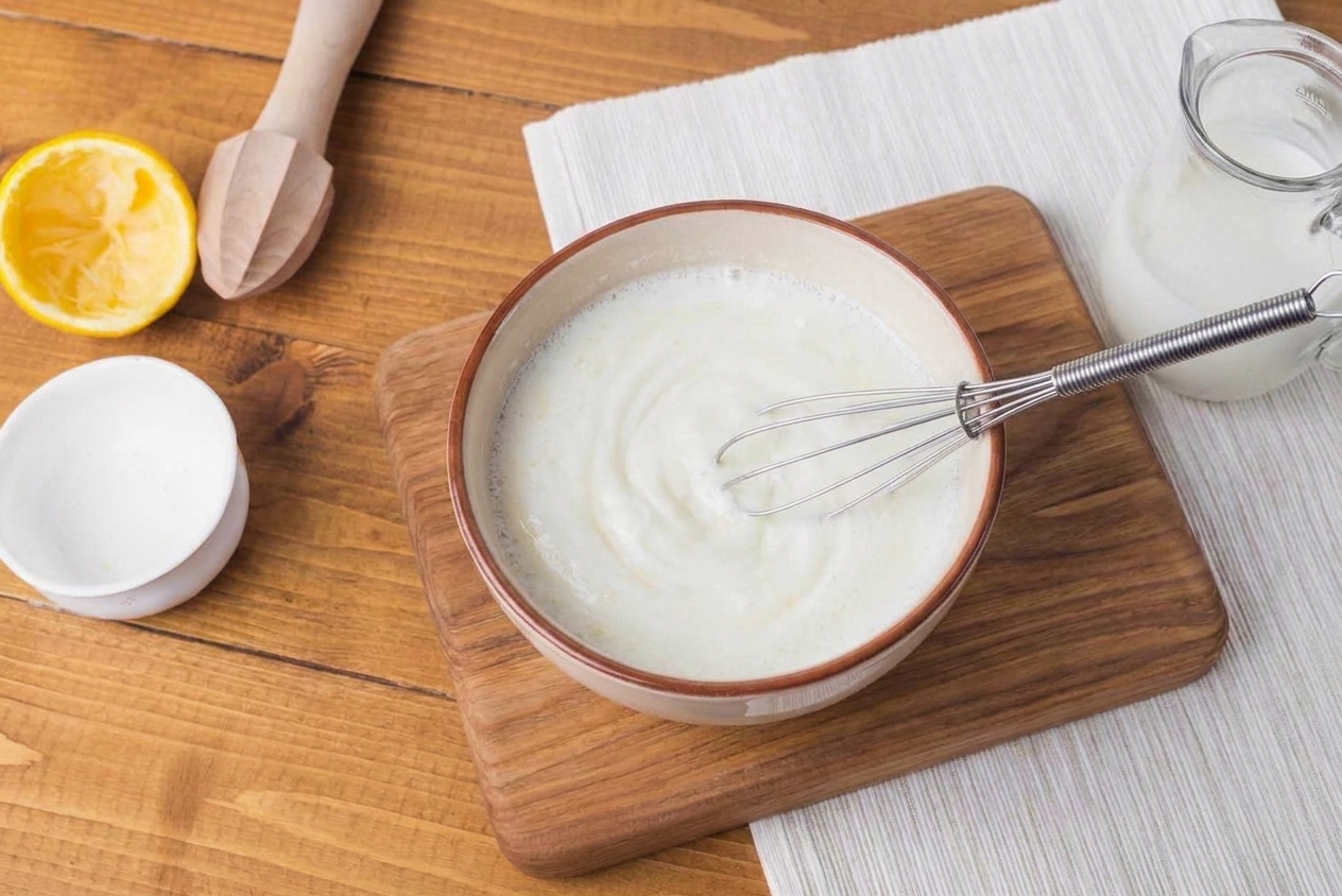 A bowl of plain yogurt being whisked with water until smooth to mimic buttermilk