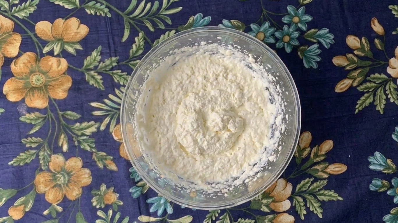 A bowl of slightly grainy overwhipped cream showing rough texture along the sides