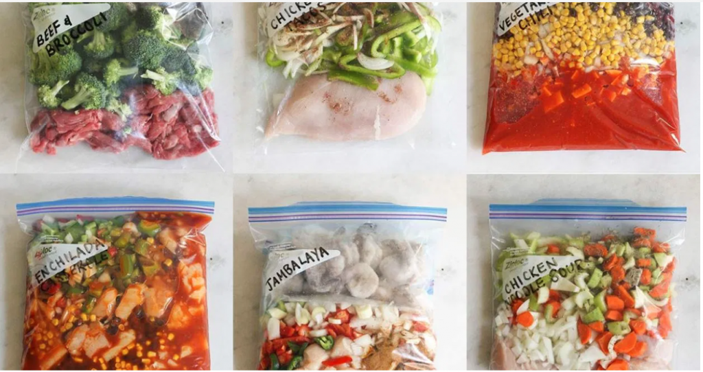 A kitchen counter with family-friendly casserole ingredients laid out, including pasta, shredded cheese, broccoli, chicken, canned tomatoes, and foil pans