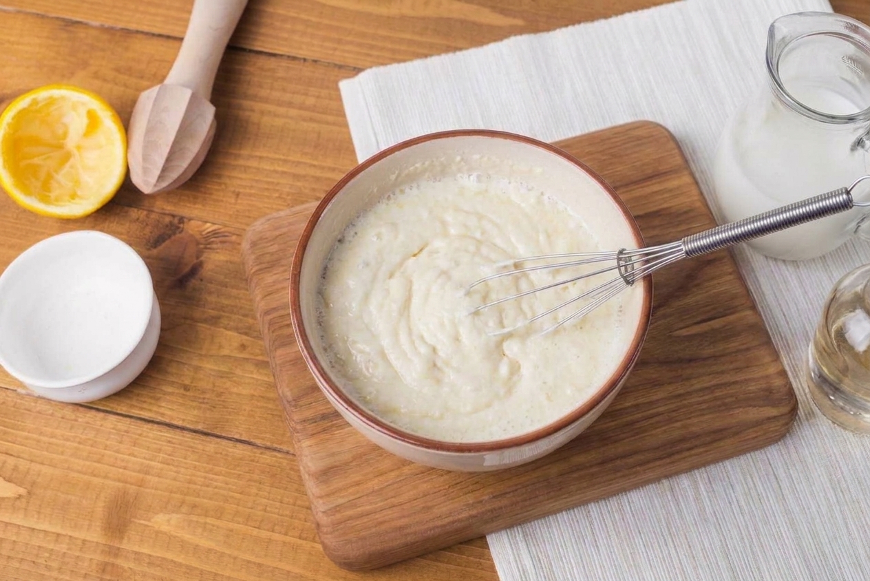 A mixing bowl of pancake batter being whisked on a kitchen counter, showing a thick, pourable texture made with a buttermilk substitute