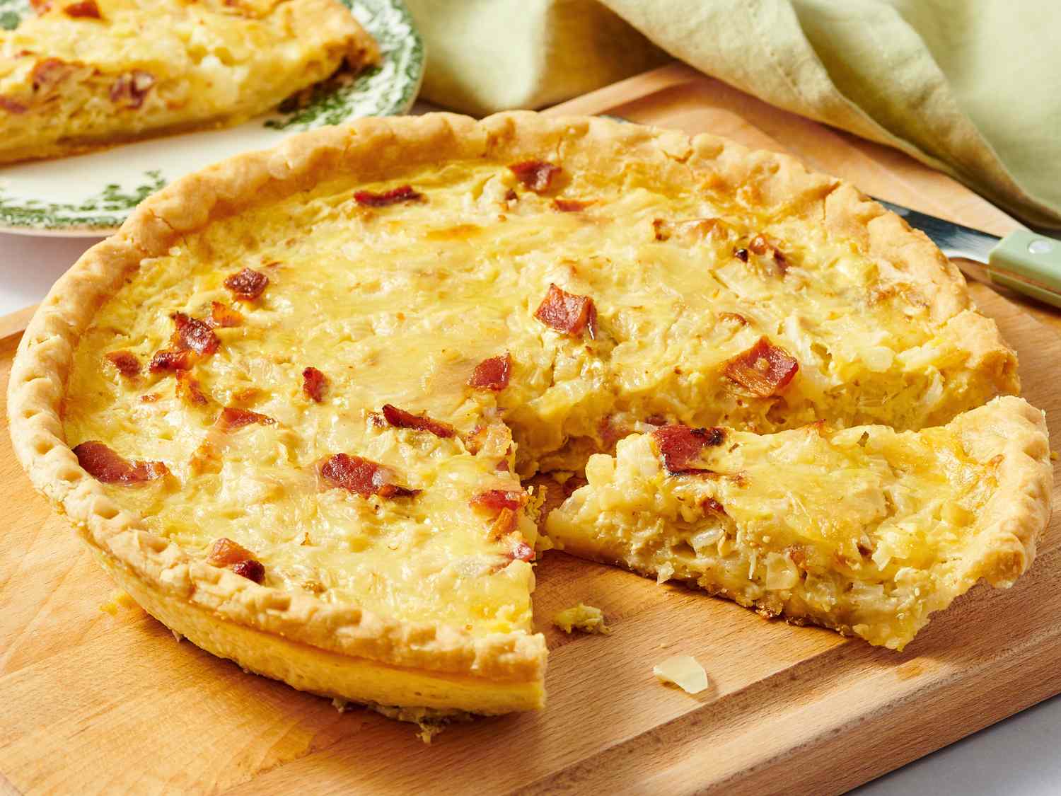 A single slice of classic quiche on a white plate, showing a pale golden, tender custard interior and a crisp browned crust