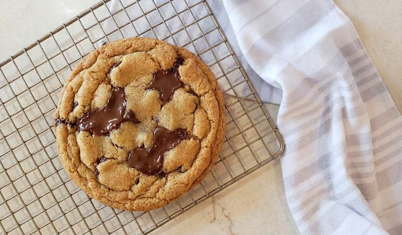 A soft brown sugar cookie with melted chocolate chips cooling on a rack