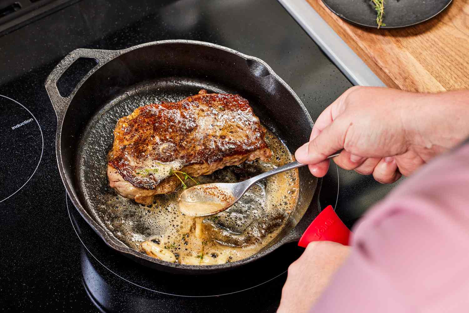 A wide stainless steel skillet heating on a stovetop burner, empty and ready for cooking