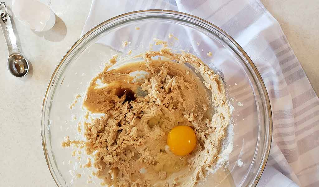 Brown sugar, butter, eggs, and vanilla arranged next to flour and baking soda on a kitchen counter